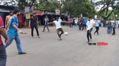 কয়েকজন শিক্ষার্থী ফুটবল নিয়ে মহাসড়কের মধ্যে খেলতে থাকেন