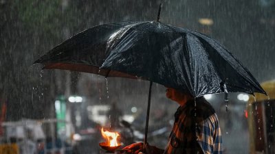 কলকাতায় ভারী বর্ষণের সময় এক ব্যক্তি ছাতা মাথায় দিয়ে যাচ্ছেন। ছবি: পিটিআই