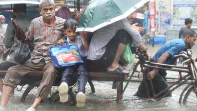 বৃষ্টি আর জলজটে ভ্যানে চড়ে স্কুলে যাচ্ছে এক শিশু শিক্ষার্থী, ছবি: নাসিরুল ইসলাম