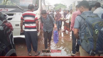 কাদাপানি মাড়িয়ে বাসে উঠছেন যাত্রীরা