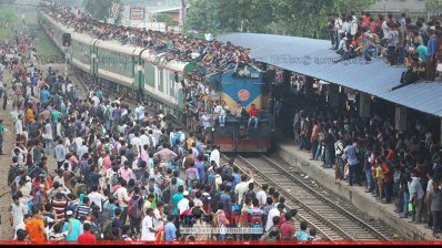 ট্রেনের ছাদে উঠতে প্ল্যাটফর্মের ছাউনিতে বসে আছেন মানুষজন