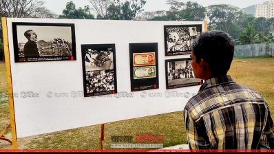 স্থিরচিত্রে তুলে ধরা মুক্তিযুদ্ধের ইতিহাস পড়ছেন একজন