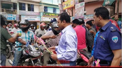 হেলমেট ব্যবহারকারীদের ফুল দিচ্ছেন পুলিশ কর্মকর্তারা 