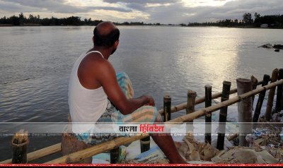 বাধেঁর ওপর বসা আমিনুর রহমান। তিস্তার ভাঙনে নদীগর্ভে হারিয়েছেন ঘরবাড়ি