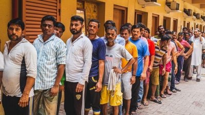 দাতব্য প্রতিষ্ঠানের খাবারের অপেক্ষায় লাইন ধরে দাঁড়ানো বেতনহীন বিদেশি কর্মীরা