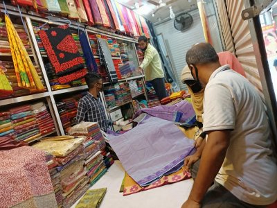 দোকানের শাটার অর্ধেক নামানো, ভেতরে ক্রেতা