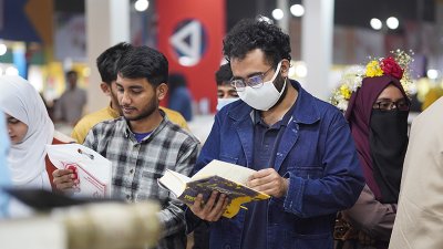 স্টলে দাঁড়িয়ে বই পড়ছেন এক পাঠক