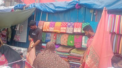 ক্রেতাদের শাড়ি দেখাচ্ছে দোকানি