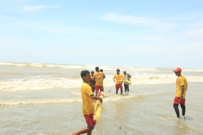 ভেসে যাওয়া এক পর্যটককে উদ্ধার করে নিয়ে যাচ্ছেন লাইফগার্ডের সদস্যরা