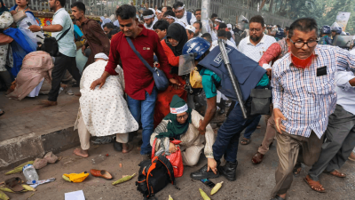 পড়ে যাওয়া এক শিক্ষিকার হাত ধরে তোলার চেষ্টা করছেন পুলিশের এক সদস্য (ছবি: আহাদুল করিম খান)