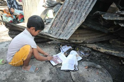 আগুনে পুড়ে যাওয়া বই হাতে নিয়ে দেখছেন এক শিশু (ছবি: নাসিরুল ইসলাম)