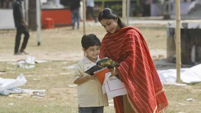 এক শিশুকে বই খুলে দেখাচ্ছেন তার মা (ছবি: নাসরিুল ইসলাম)