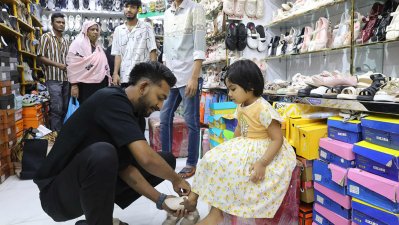শিশুকে ঈদের জুতা কিনে দিচ্ছেন বাবা, ছবি: নাসিরুল ইসলাম