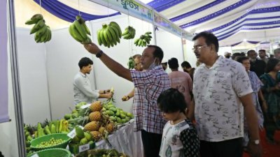 মেলায় দেশি কলা ধরে দেখছেন দর্শনার্থীরা