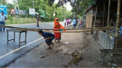 বাঁশের ব্যারিকেডের নিচ দিয়ে মানুষের চলাচল
