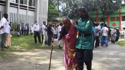টিকা নেওয়া শেষে এক বৃদ্ধাকে এগিয়ে দিচ্ছেন নারী পুলিশ সদস্য।