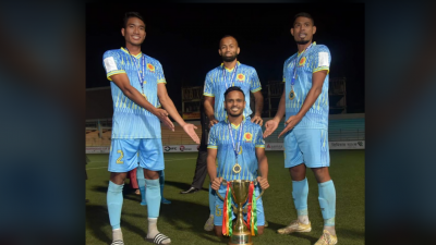 ট্রফির সামনে বসে হাস্যোজ্জ্বল ইমন মাহমুদ, দুই পাশে দাঁড়িয়ে সুশান্ত ত্রিপুরা ও নুরুল নাইম ফয়সাল। আর ইমনের পিছনে আরেক ডিফেন্ডার রেজাউল করিম।