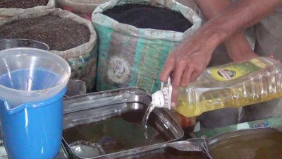 বোতল থেকে ঢেলে ড্রামে সয়াবিন তেল রাখছে দোকানিরা