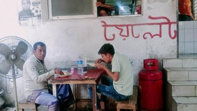 গণশৌচাগারের প্রবেশদ্বারের পাশেই চেয়ার টেবিল বসে খাবার খাচ্ছেন অনেকে