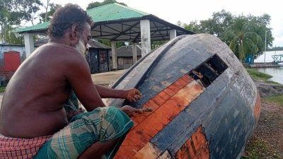 অবসরে নিজের নৌকাটি ঠিক করে নিচ্ছেন এই জেলে