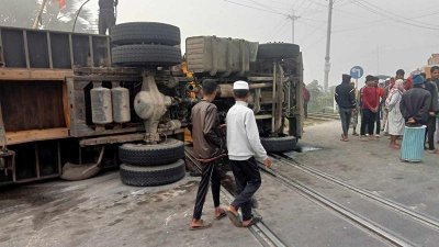 রেললাইনে উল্টে পড়া লরি
