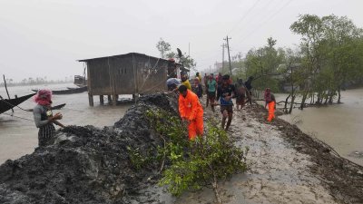 বেড়িবাঁধ উপচে জনবসতিতে ঢুকে পড়া পানি আটকানোর চেষ্টা