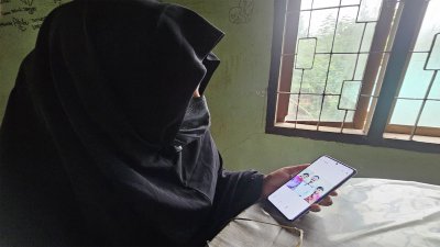 মোবাইল ফোনে দুই মেয়ের সঙ্গে নিহত স্বামী একরামুল হকের ছবি দেখছেন আয়েশা বেগম