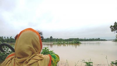 যেকোনও সময় ভেঙে যেতে পারে বাঁধ। অসহায় তাকিয়ে আছে নদী পাড়ের একজন বাসিন্দা। ছবি: প্রতিবেদক