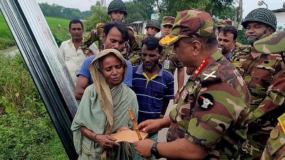 ক্ষতিগ্রস্ত একজনকে নগদ টাকা ও টিন দিচ্ছেন সেনা কর্মকর্তারা