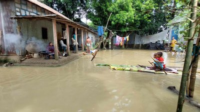 বারান্দায় চলছে রান্নাবান্না, উঠানের পানিতে ভেলায় ভাসছে দুই শিশু (ছবি: বাংলা ট্রিবিউন)