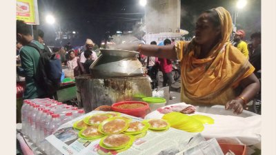 ভাপা পিঠা বানিয়ে ক্রেতাদের জন্য সাজিয়ে রাখছেন এই নারী বিক্রেতা