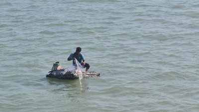 নাফ নদে জাল ফেলে মাছ ধরছেন একজন