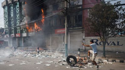 আগুন ধরানো টায়ারে লাথি মারছেন এক বিক্ষোভকারী। ছবি: রয়টার্স