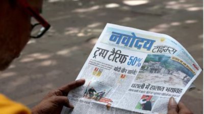 নয়াদিল্লির বাজারে ভারতীয় পণ্যের ওপর অতিরিক্ত শুল্ক আরোপের খবর পড়ছেন এক ব্যক্তি। ছবি: রয়টার্স।
