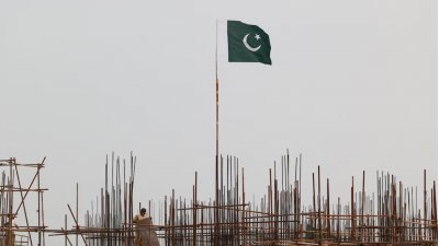 লাহোর একটি নির্মাণস্থলে শ্রমিকরা কাজ করছেন। আর লোহার নকশার ওপর পাকিস্তানের পতাকা উড়ছে। ছবি: রয়টার্স।