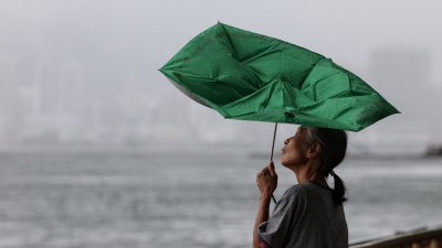 মৌসুমি ঝড় ট্যাপা ঘনিয়ে আসার সময় বাতাসে উল্টে যাওয়া ছাতা হাতে এক নারী। ছবি: রয়টার্স।