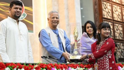 বিজয়ীর হাতে ক্রেস্ট তুলে দিচ্ছেন প্রধান উপদেষ্টা অধ্যাপক মুহাম্মদ ইউনূস, পাশে সম্প্রচার উপদেষ্টা মোঃ মাহফুজ আলম
