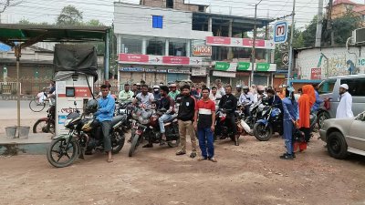 মোটরসাইকেল ও অন্যান্য পরিবহন ফিলিং স্টেশনের সামনে তেল নেওয়ার জন্য অপেক্ষা করছে