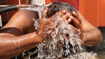 তীব্র গরমে মাথায় পানি দিচ্ছেন এক ব্যক্তি